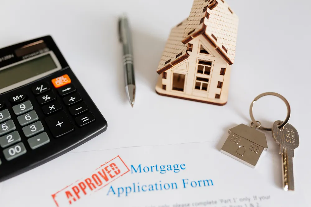 House figure next to house keys and a mortgage application form on a white background
