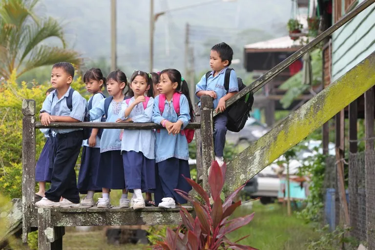 Primary school students lounging outside of school building in a rural area