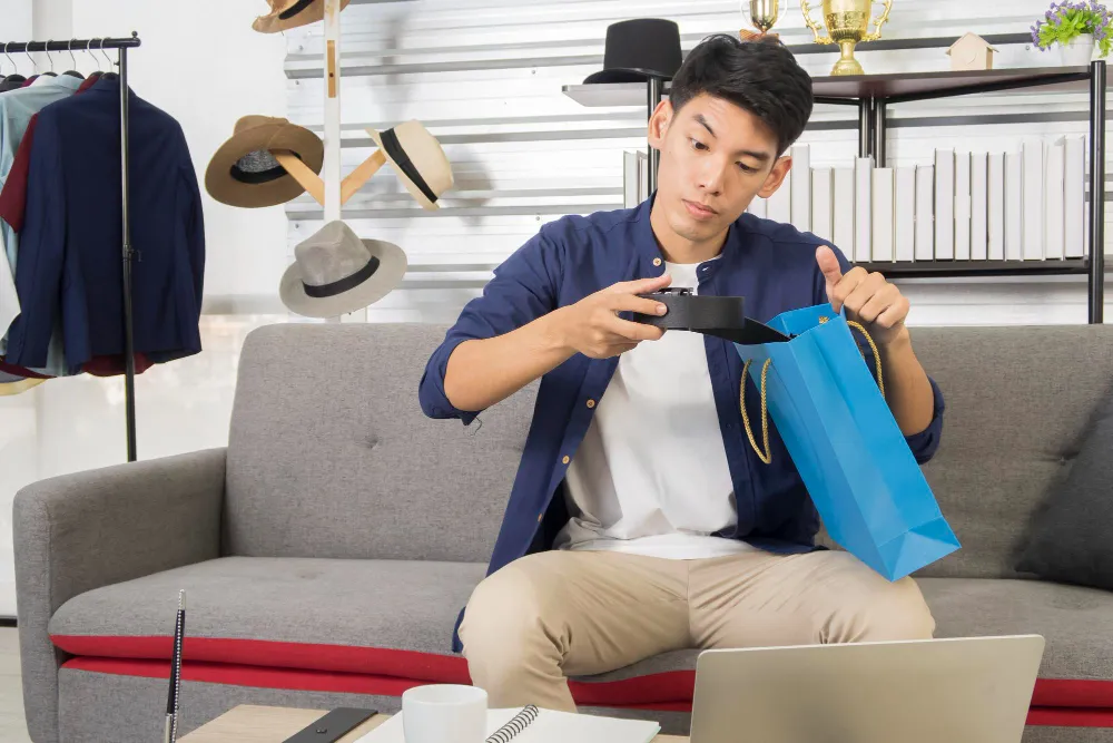 Asian sitting on couch unboxing a new package